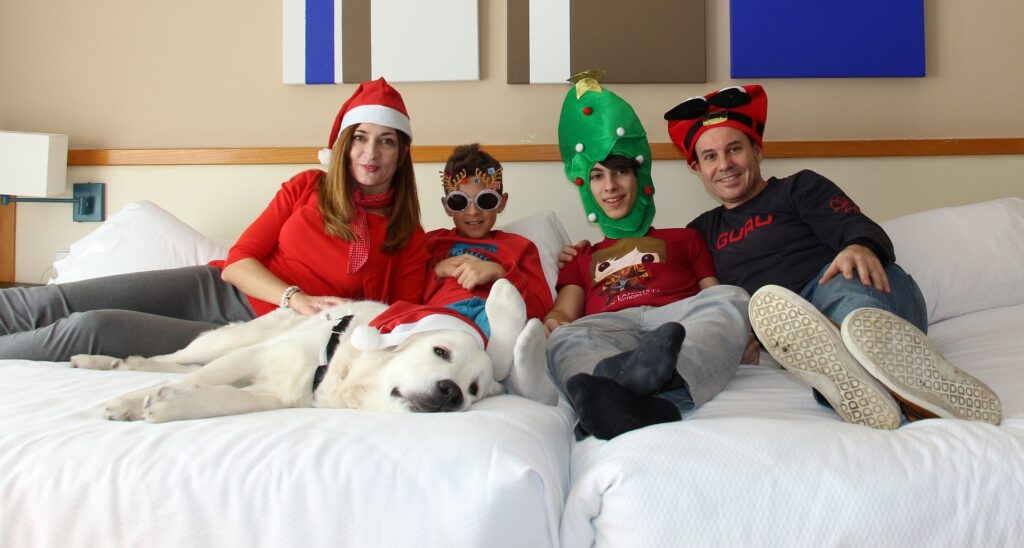 A Christmas picture of a family and a dog posing on a bed